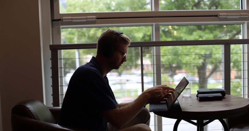 Man with headphones listening to music and working at Roam Innovative Workplace