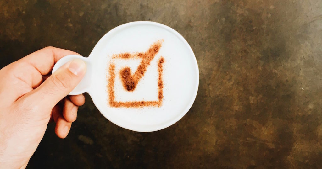 Hand holding mug with check box latte art